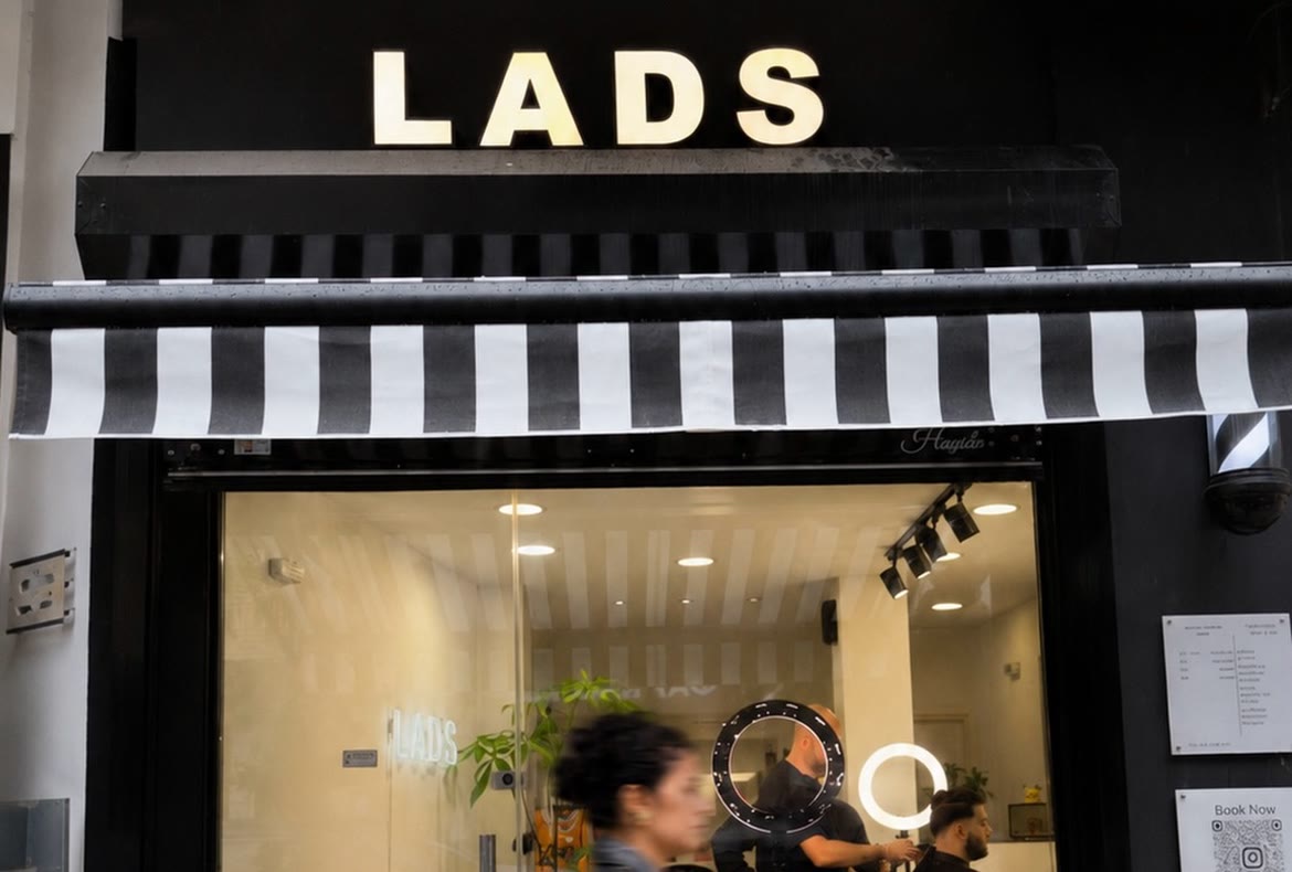 Η μαύρη βιτρίνα του Lads Hair Concept στη Δελφών 82, με τα άσπρα γράμματα LADS